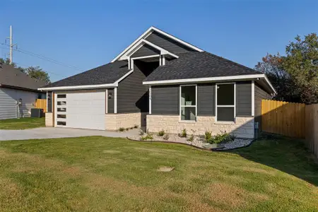 View of front facade featuring a front yard, a garage, and central air condition unit