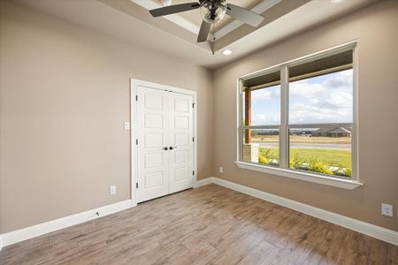 Unfurnished bedroom with a raised ceiling, ceiling fan, ornamental molding, light hardwood / wood-style floors, and a closet