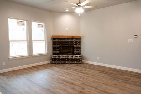Unfurnished living room with a fireplace, hardwood / wood-style flooring, and ceiling fan
