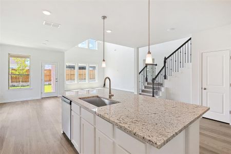 Kitchen with light hardwood / wood-style flooring, a kitchen island with sink, white cabinetry, light stone countertops, and sink