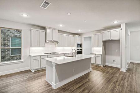 Kitchen featuring stainless steel appliances, dark hardwood / wood-style flooring, white cabinetry, sink, and an island with sink