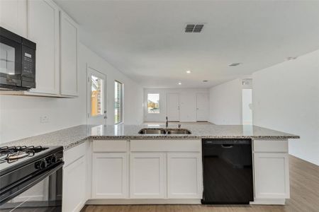 Kitchen with light hardwood / wood-style floors, sink, white cabinetry, and black appliances