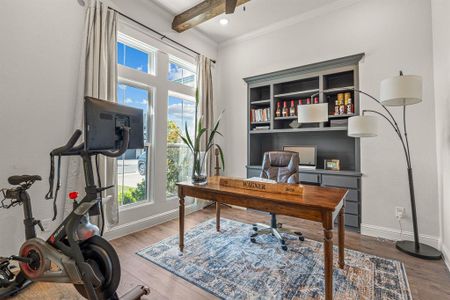 Home office featuring crown molding, a healthy amount of sunlight, beam ceiling, and wood-type flooring