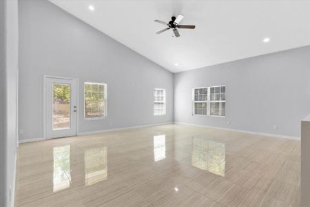 Unfurnished living room featuring high vaulted ceiling, ceiling fan, and light tile patterned floors