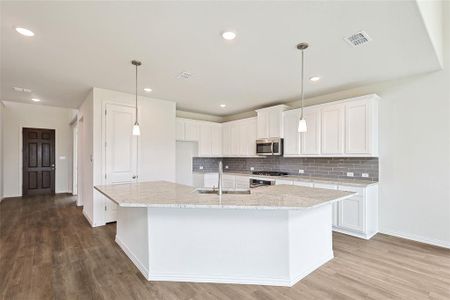 Kitchen with a center island with sink, sink, light wood-type flooring, and white cabinets