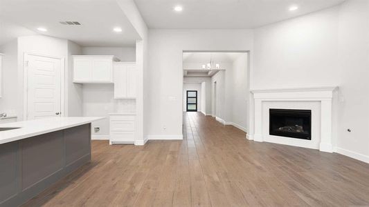 Unfurnished living room with a notable chandelier, sink, and light hardwood / wood-style flooring