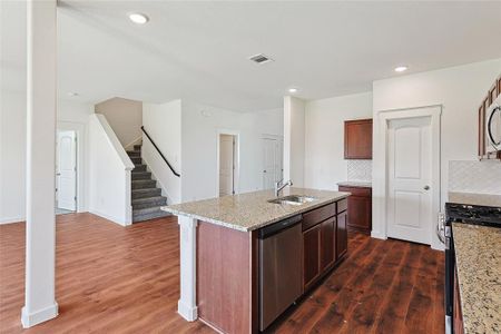 Kitchen with a center island with sink, stainless steel appliances, backsplash, and dark wood-type flooring