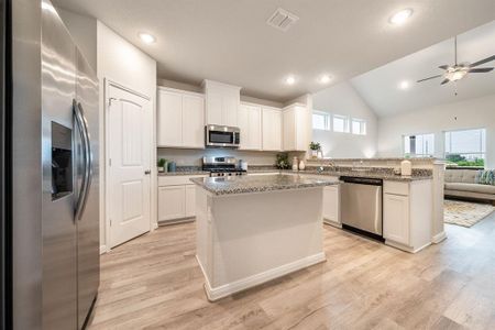 This kitchen is truly a chef's dream! This haven boasts high ceilings, recessed  lighting, light wood cabinets, granite countertops, stainless steel appliances, a modern tile backsplash.  All of this overlooks your expansive family room, creating a perfect space for culinary delights and family gatherings. Sample photo of completed home. Actual color and selections may vary.