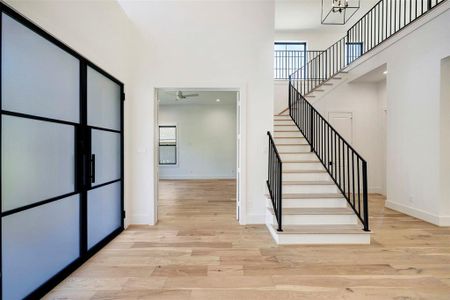 SAMPLE - Light-filled foyer features dramatic, soaring ceiling. View toward the study and the custom wrought iron staircase with solid oak treads. Gorgeous wide plank, natural finish, engineered wood floors throughout.