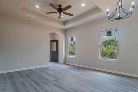 Unfurnished room featuring hardwood / wood-style flooring, a raised ceiling, and ceiling fan with notable chandelier