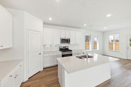 Kitchen featuring white cabinetry, appliances with stainless steel finishes, a kitchen island with sink, sink, and tasteful backsplash
