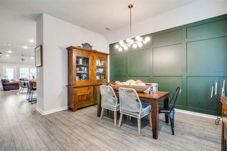 Dining space with ceiling fan with notable chandelier, lofted ceiling, and light hardwood / wood-style flooring