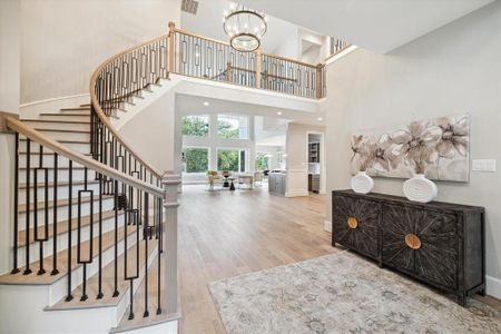 This is a breath taking home as you enter this spacious, open-concept interior featuring a sweeping staircase with modern metal balusters, high ceilings and abundant natural light. The view from the foyer shows a well-appointed living area and hints at a gourmet kitchen beyond.