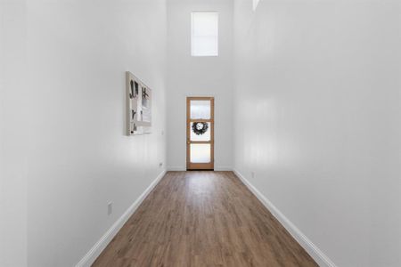 Doorway to outside featuring a towering ceiling and wood-type flooring