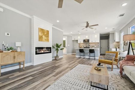 Living room featuring a large fireplace, ceiling fan, plenty of natural light, and hardwood / wood-style floors