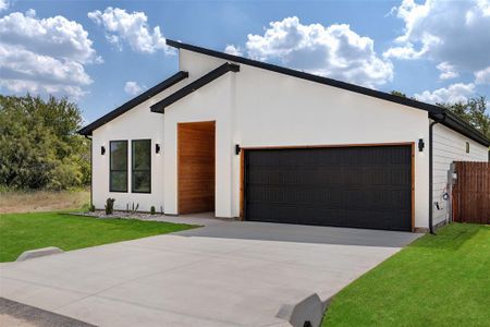 View of front of property featuring a garage and a front lawn