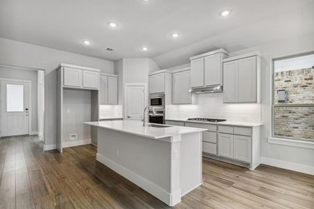 Kitchen featuring light hardwood / wood-style floors, a center island with sink, sink, appliances with stainless steel finishes, and backsplash