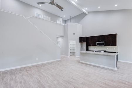 Kitchen with beam ceiling, decorative backsplash, light hardwood / wood-style flooring, and high vaulted ceiling