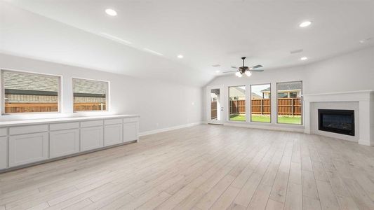 Unfurnished living room with a fireplace, ceiling fan, lofted ceiling, and light hardwood / wood-style floors