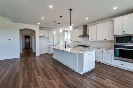 Kitchen featuring white cabinetry, stainless steel appliances, and wall chimney exhaust hood