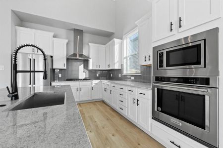 Kitchen includes a black iron cook-top with sleek, steel vent hood.