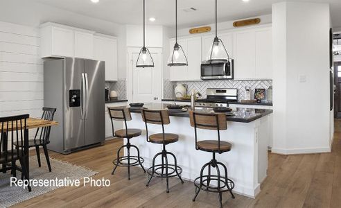 Kitchen with a kitchen island with sink, appliances with stainless steel finishes, light hardwood / wood-style floors, and pendant lighting