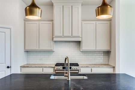 Kitchen featuring sink, tasteful backsplash, white cabinetry, and stainless steel gas stove