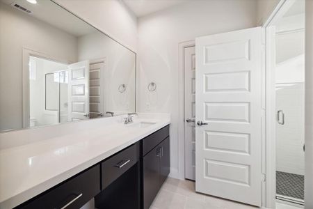 This sleek first-floor bathroom features a large vanity with plenty of counter space and dark cabinetry for a modern, elegant look.