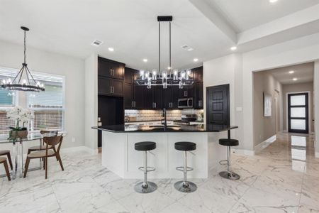 Kitchen with tasteful backsplash, decorative light fixtures, a kitchen bar, a kitchen island with sink, and appliances with stainless steel finishes