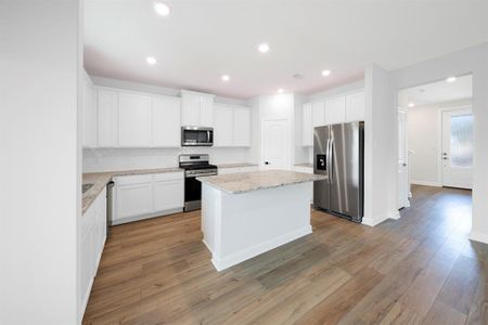 The neutral palette of white cabinets, stainless steel appliances, and granite countertops offers a versatile foundation for personalization and decor accents, allowing homeowners to easily adapt the kitchen's aesthetic to suit their individual tastes and preferences.