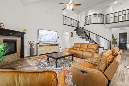 Living room with wood-type flooring, a high ceiling, a fireplace, and ceiling fan