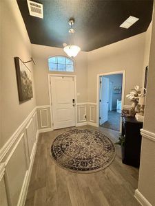 Entrance foyer with a textured ceiling and dark hardwood / wood-style flooring