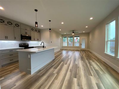 Kitchen featuring a center island with sink, hardwood / wood-style floors, appliances with stainless steel finishes, sink, and ceiling fan