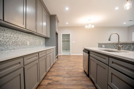 Kitchen with tasteful backsplash, dishwasher, dark hardwood / wood-style floors, decorative light fixtures, and sink