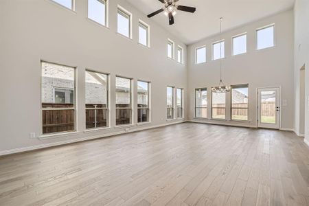 Unfurnished living room with light hardwood / wood-style flooring, a high ceiling, and plenty of natural light