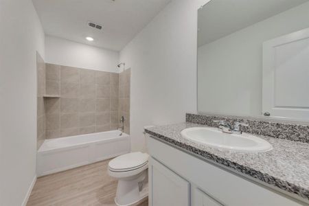 Full bathroom featuring vanity, toilet, hardwood / wood-style flooring, and tiled shower / bath