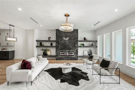 Living room featuring a premium fireplace, a chandelier, and light wood-type flooring