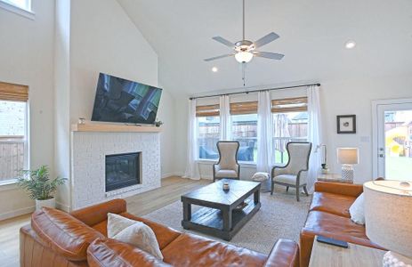 Living room featuring high vaulted ceiling, ceiling fan, light engineered hardwood floors, and a gas log fireplace