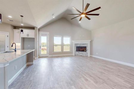 Unfurnished living room featuring high vaulted ceiling, a fireplace, ceiling fan, light hardwood / wood-style flooring, and sink