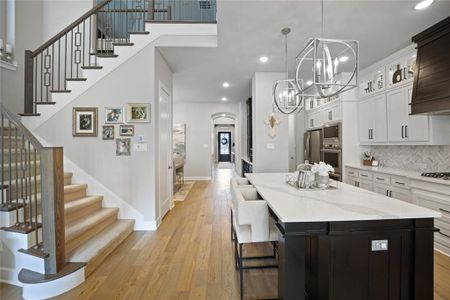 Kitchen with white cabinets, backsplash, a kitchen island, light wood-type flooring, and stainless steel appliances