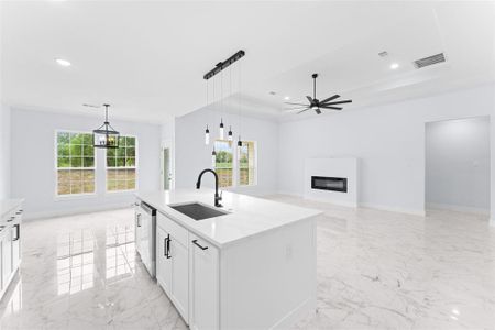 Kitchen with a kitchen island with sink, sink, ceiling fan, stainless steel dishwasher, and white cabinets