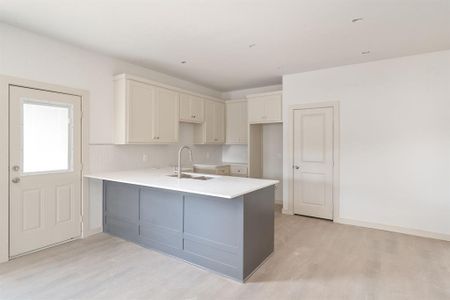 Kitchen with light wood-type flooring, white cabinetry, kitchen peninsula, and sink