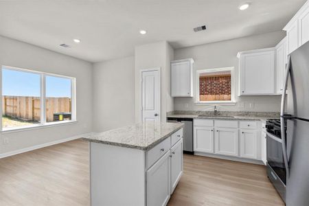 he charming kitchen has home owner favorite upgrades including dallas white granite, white cabintry, island, built in pantry, and stainless steel appliances.