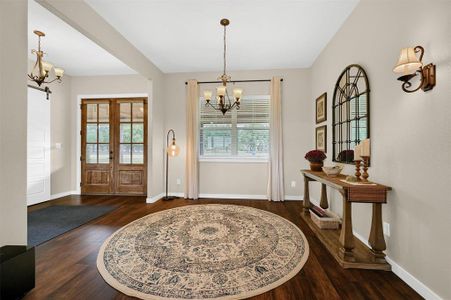 Foyer entrance with an inviting chandelier, dark wood-type flooring, a barn door, and french doors