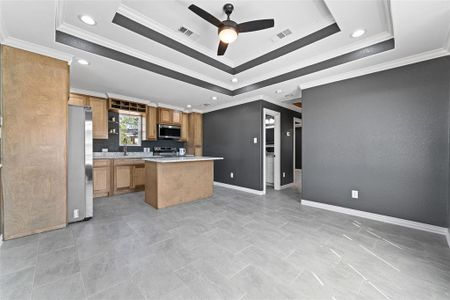 Kitchen featuring ornamental molding, a center island, appliances with stainless steel finishes, and a raised ceiling