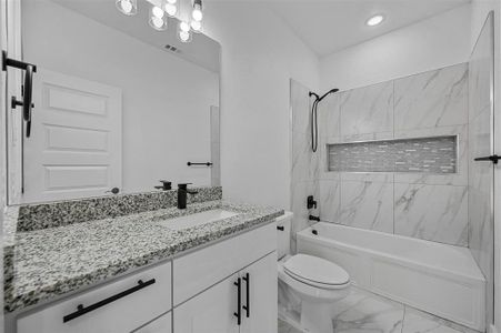 Full bathroom featuring vanity, tile patterned flooring, tiled shower / bath, and toilet