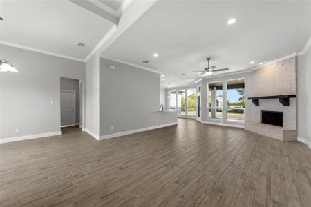 Unfurnished living room with ornamental molding, hardwood / wood-style floors, a fireplace, and ceiling fan with notable chandelier