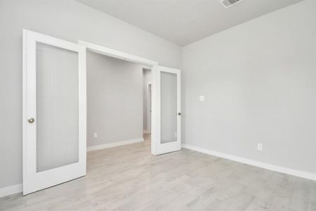 Experience the perfect blend of sophistication and warmth in this home office, boasting elegant wood-look tile flooring and flooded with natural light from expansive windows and French doors. Sample photo of completed home with similar floor plan. Actual colors and selections may vary.