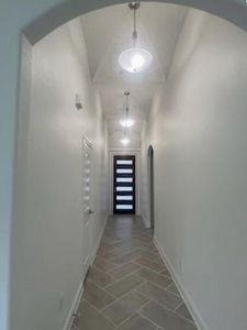 Corridor with dark tile patterned floors and lofted ceiling