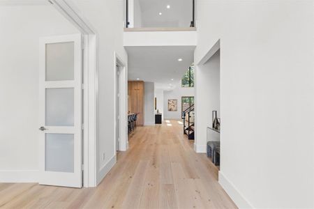 Corridor with a towering ceiling and light hardwood / wood-style floors